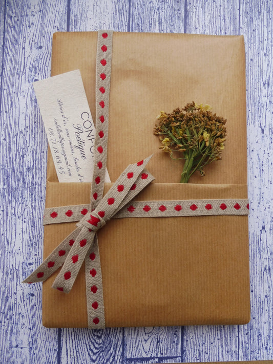Carnet A5 Mystère 60 pages, papier 110g, sur fond bleu, emballé dans un paquet cadeau de papier Kraft brun, d'un cordon beige et rouge, d'un brocoli en fleurs séchées, et d'une carte de visite Confort Poétique