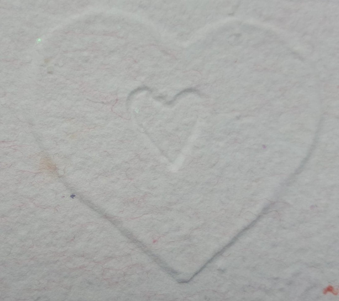 Le détail des cœurs gaufrés sur un doux papier fait main.