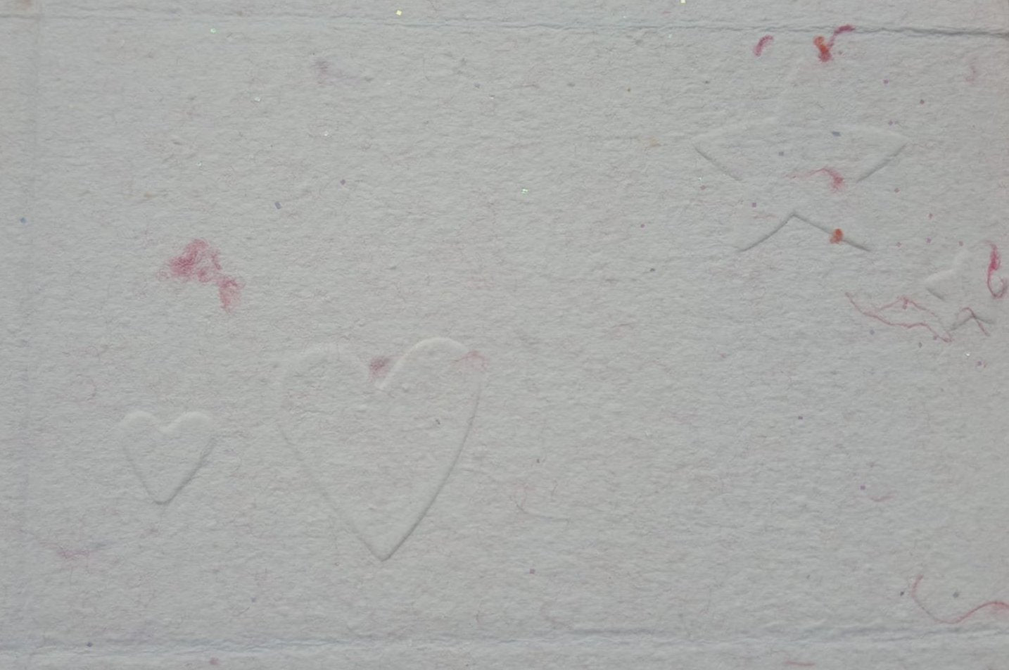 Carte gaufrée sur papier rose, les motifs sont des cœurs et des étoiles