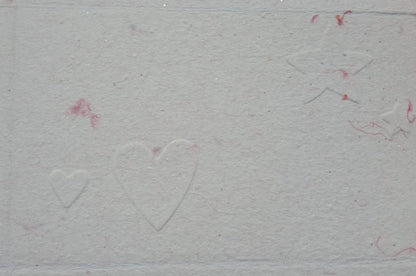 Carte gaufrée sur papier rose, les motifs sont des cœurs et des étoiles